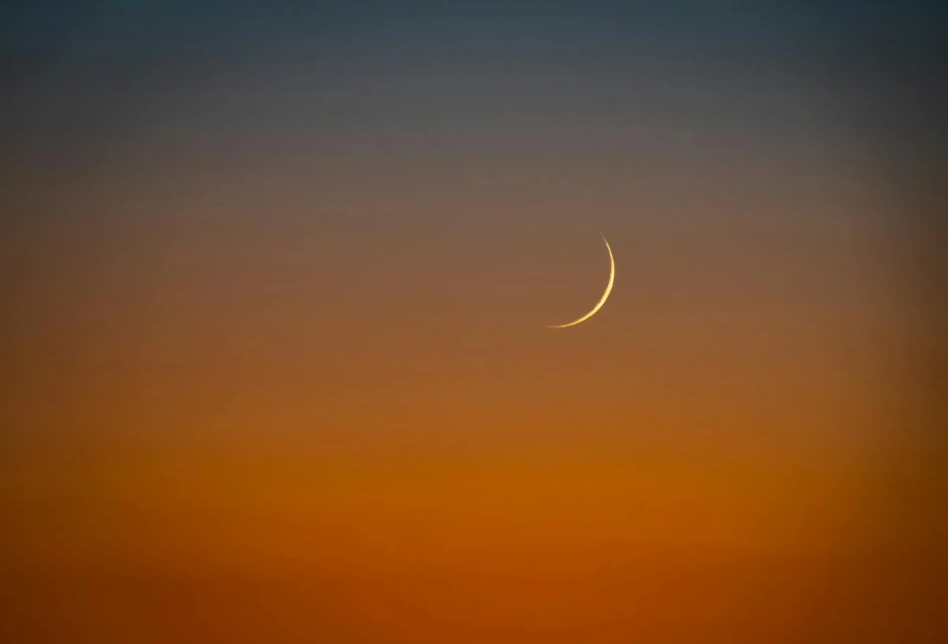 Saudi Arabia Dhul Hijjah Moon Sighted Eid al-Adha on May 27 Day of Arafah on May 26 - Nayi Soch News-e-Hub Crescent moon glowing in a gradient sunset sky, fading from orange near the horizon to deep blue above.