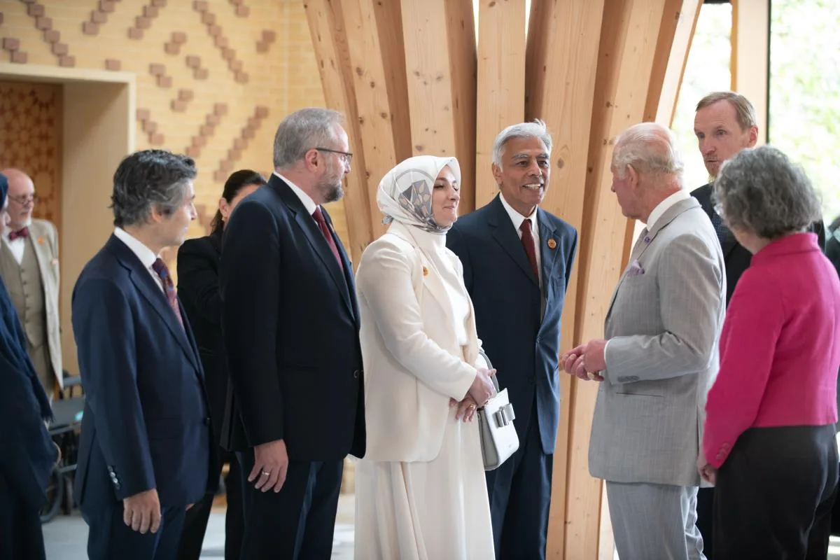 Group of formally dressed people chatting in a modern wooden interior during a formal event.